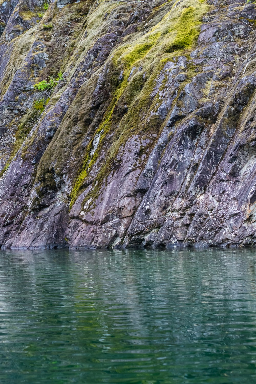 a rocky cliff next to a body of water