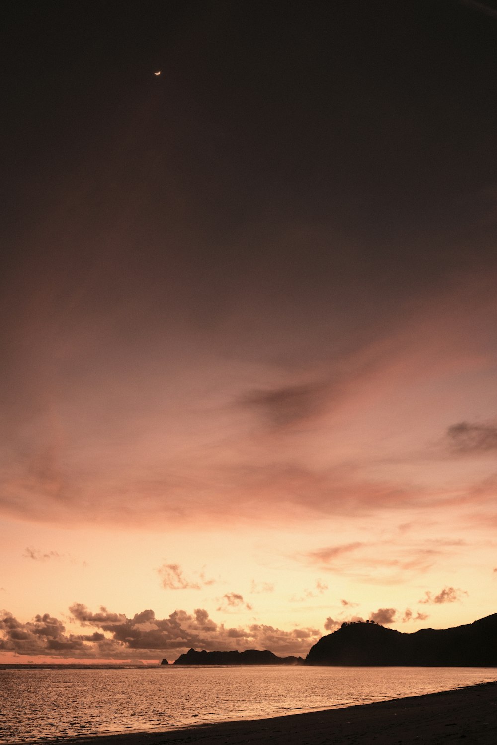 a beach with a body of water and a sunset