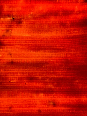 Close-up of a brush stroke texture in fiery orange and red tones on a dark background.