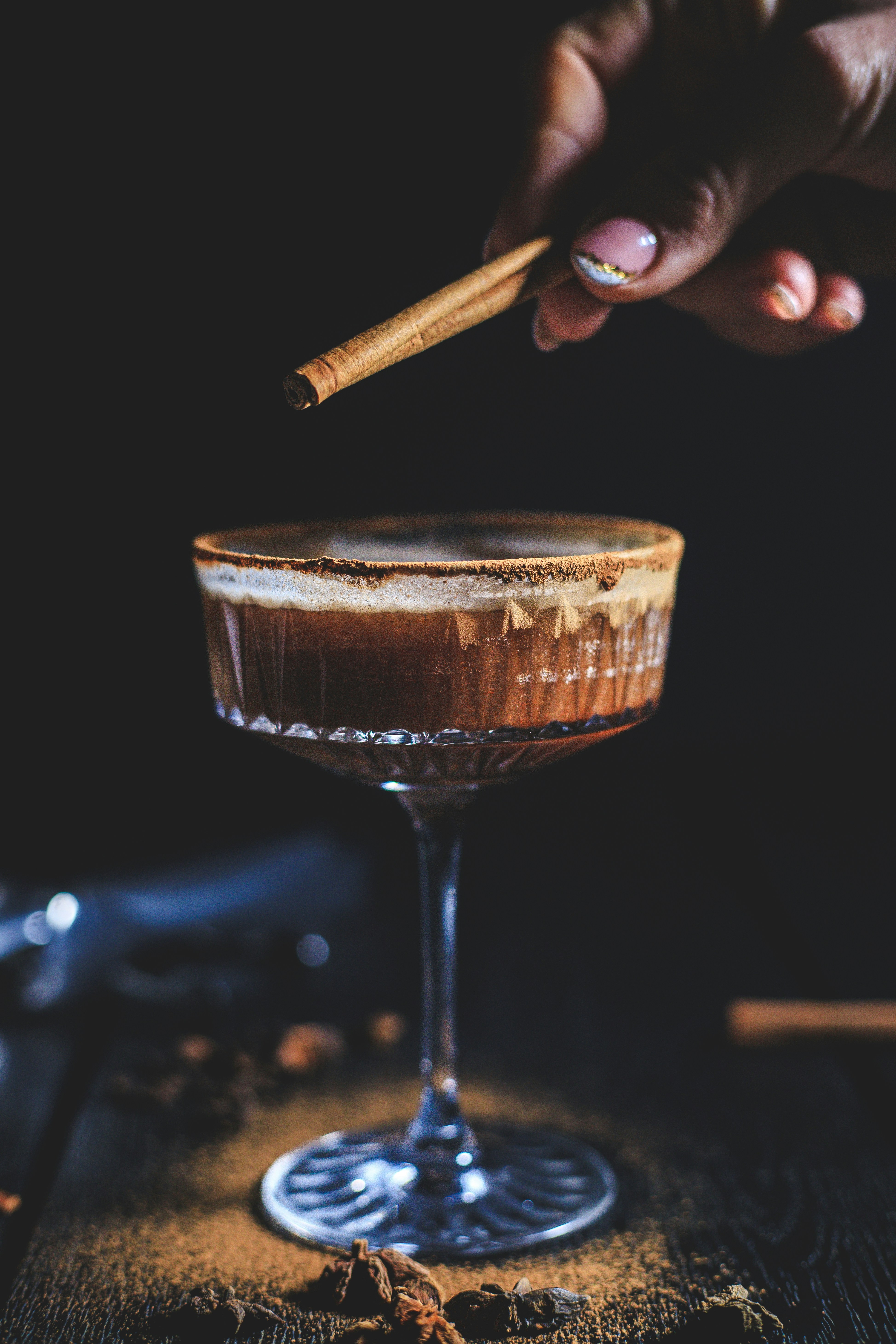 a hand holding a cigar over a glass of wine