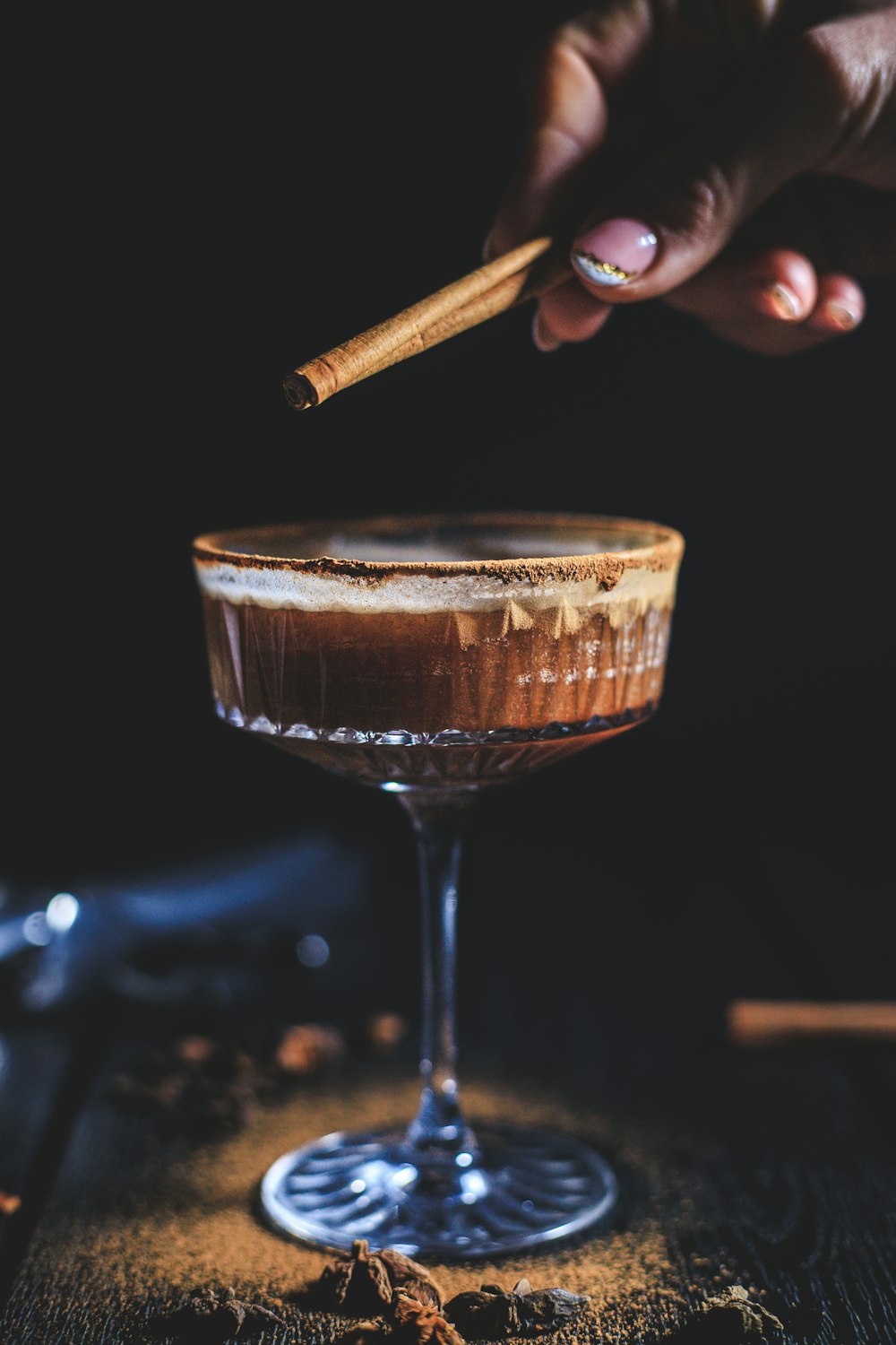 a hand holding a cigar over a glass of wine