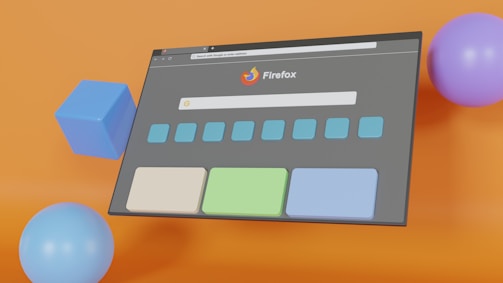 A digital illustration features a web browser interface with the Firefox logo prominently displayed. The browser window is set against a vibrant orange background and surrounded by colorful geometric shapes including a blue cube, a light blue sphere, and a purple sphere. The browser window shows a search bar and several rectangular buttons below it.