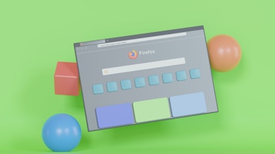 A tilted browser window, featuring the Firefox logo and search bar, is displayed against a vibrant green background. Surrounding the window are colorful 3D geometric shapes, including a red cube, a blue sphere, and an orange sphere.