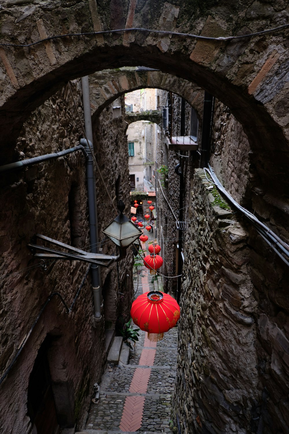 a stone walkway with lanterns from the ceiling