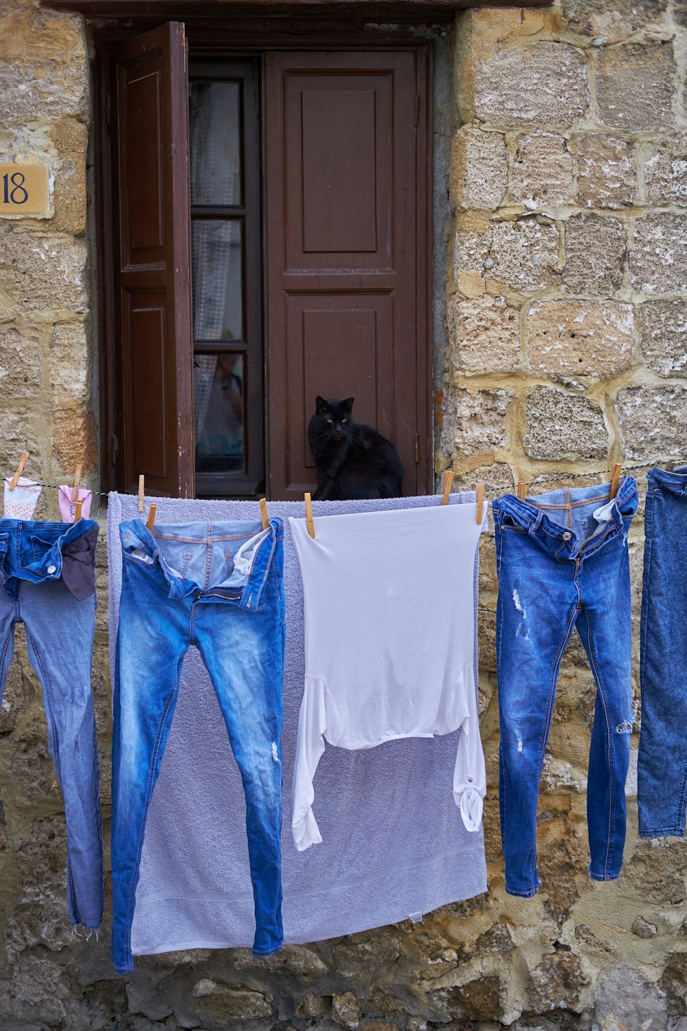 a cat sitting on a rack of clothes outside a door