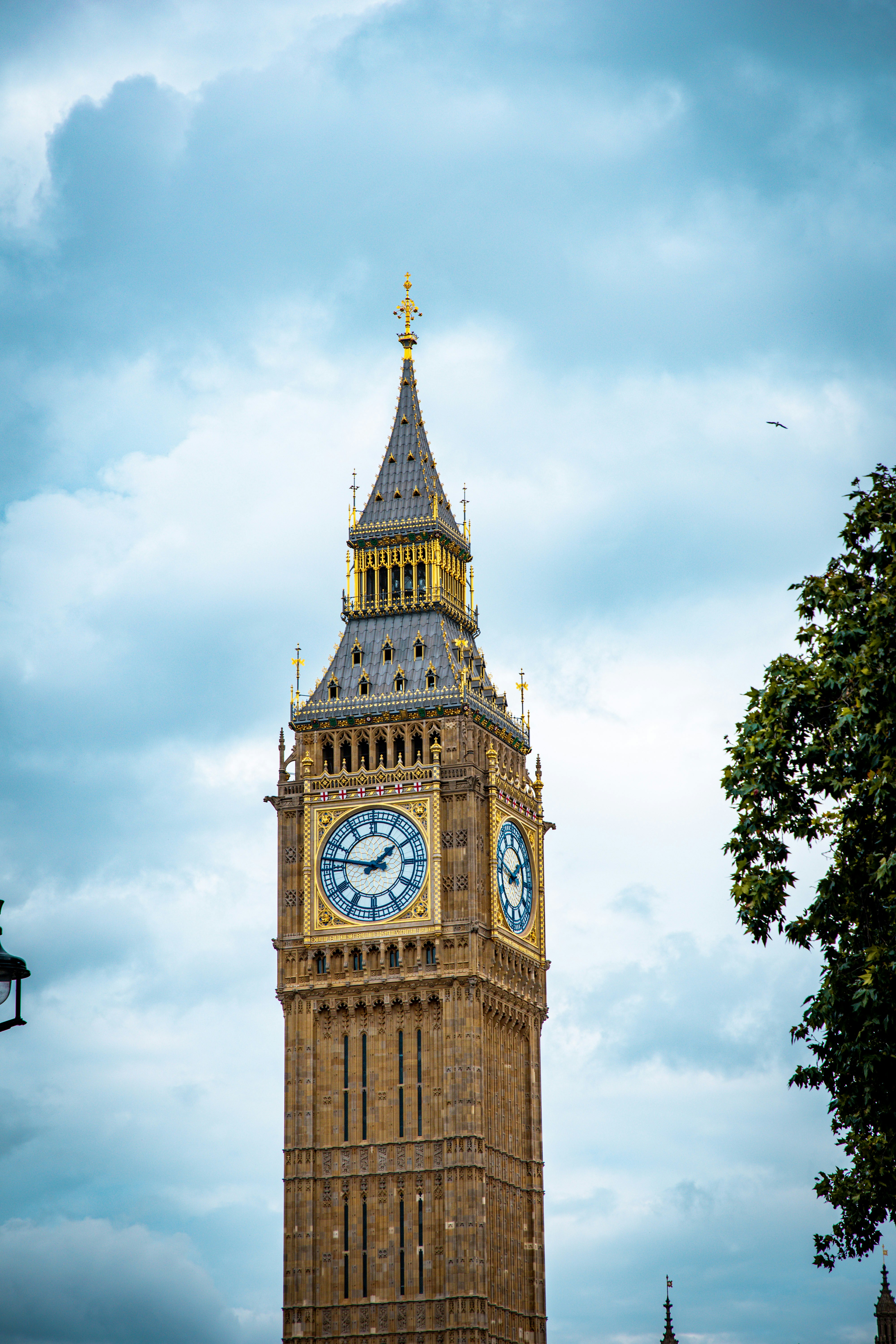 a clock tower with a weather vane with Big Ben in the background