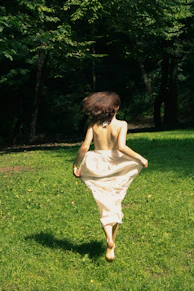 a person in a dress running in a grassy area