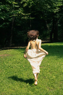 a person in a dress running in a grassy area