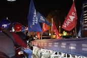 A Banner Biker with glowing transition lights on the bike and trailing double-sided flag banners in bright colors.
