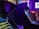 A dimly lit arcade with several classic arcade game machines in view. Neon lights glow, casting a purple and blue hue over the environment. Some text is visible on the game screens, with one machine having a prominent display of game features. The area seems to be bustling with activity with a few blurred figures visible in the background.