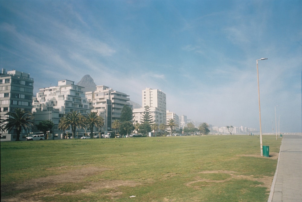 a grassy area with buildings in the background