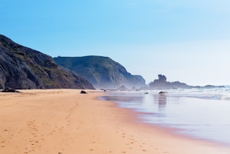 a sandy beach with hills in the background