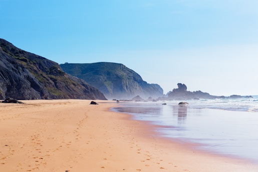 a sandy beach with hills in the background