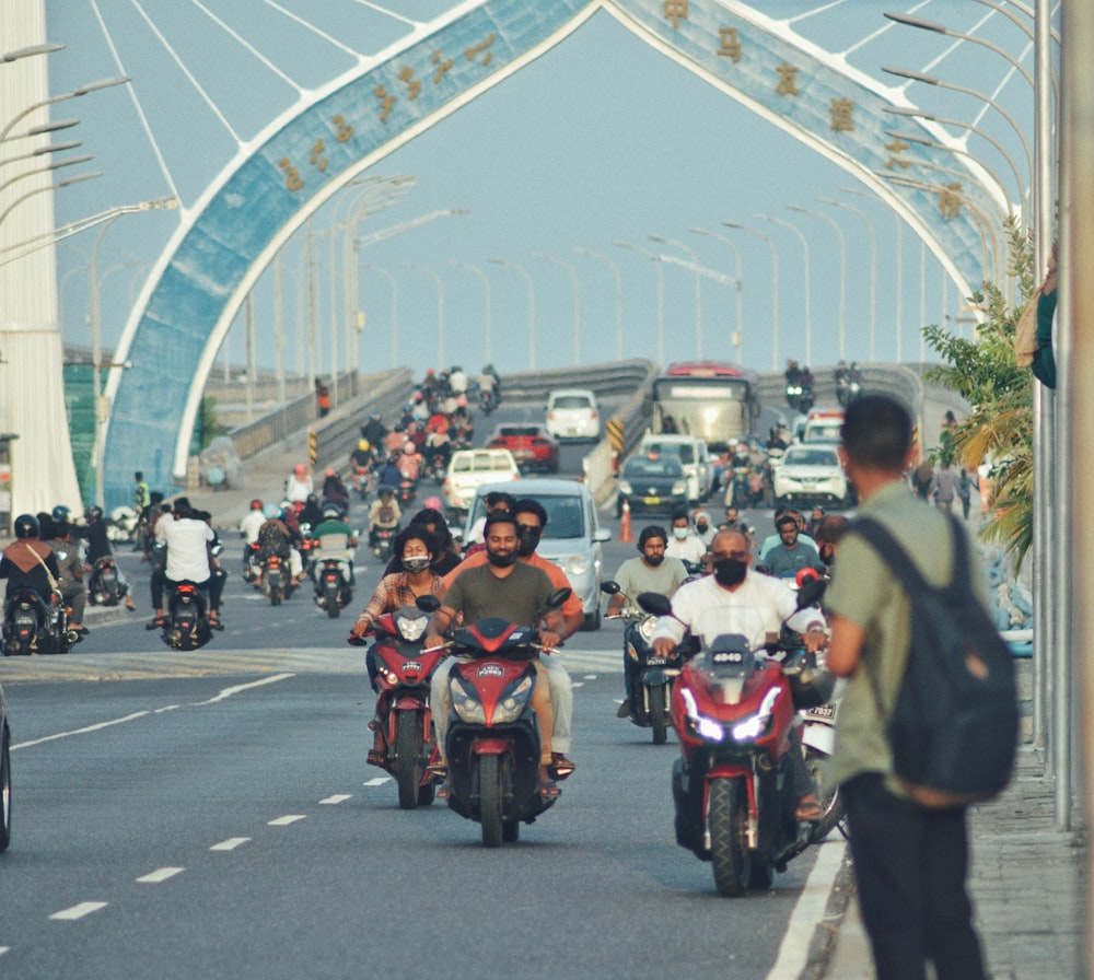 a group of people ride motorcycles under a bridge