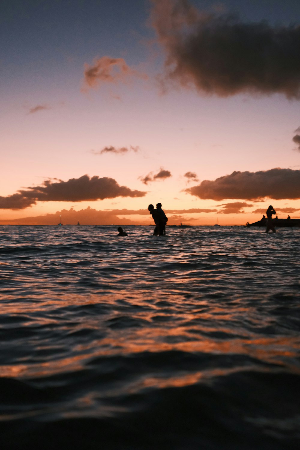 a group of people standing in the water at sunset