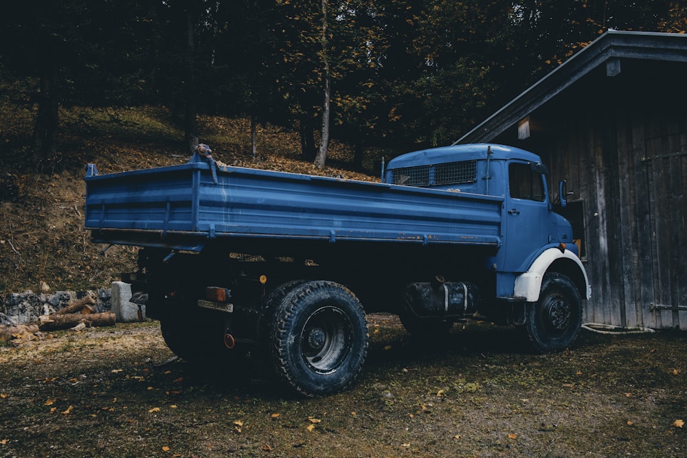 a blue truck parked in front of a wooden building