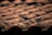 Rows of terracotta roof tiles are neatly aligned, with visible signs of weathering and aging. The tiles have a natural reddish-brown color with patches of dark discoloration, possibly due to moss or dirt.