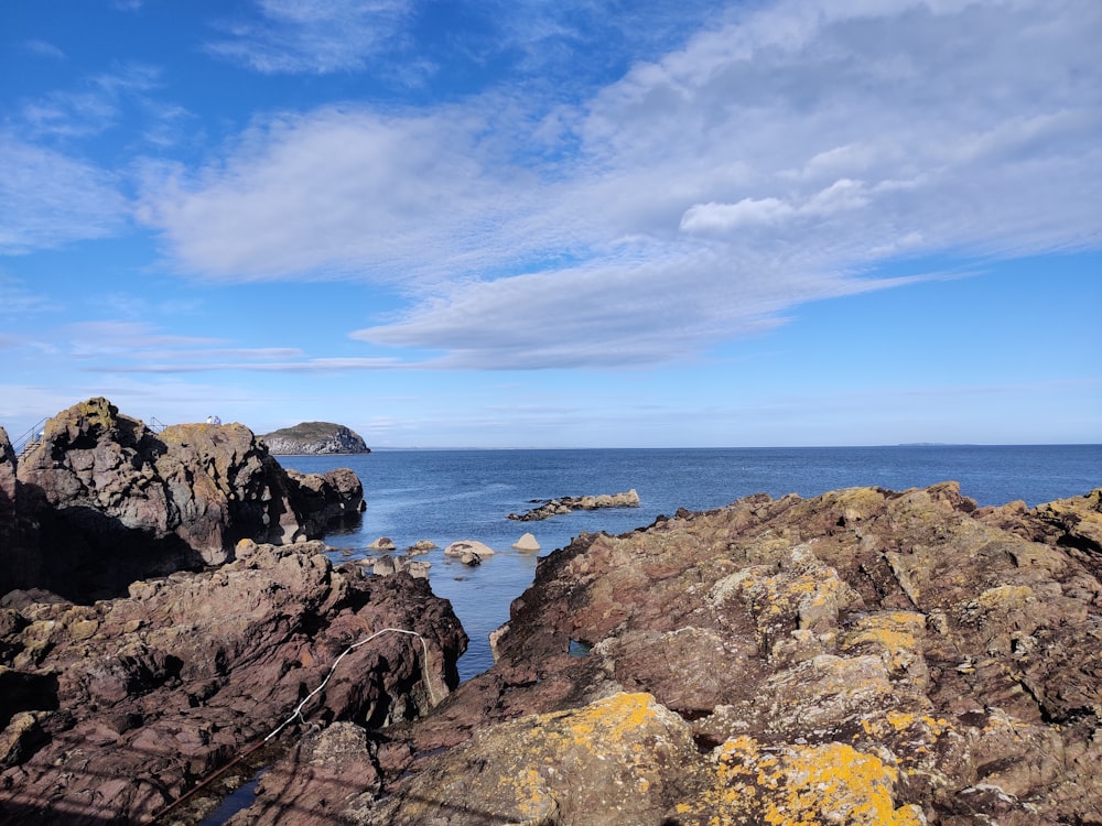 a rocky beach with a body of water in the background