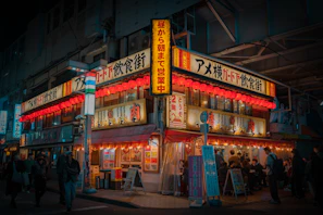 A lively group enjoying their meal at Japones, surrounded by vibrant neon signs and dark stylish walls.