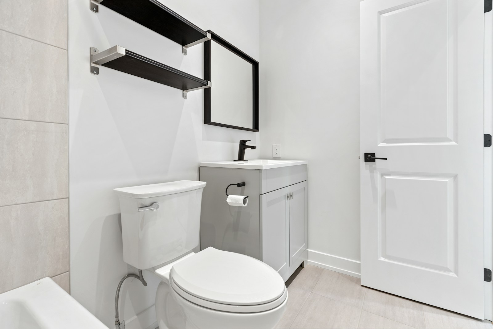 small modern rental bathroom with dark floating shelves toilet and vanity