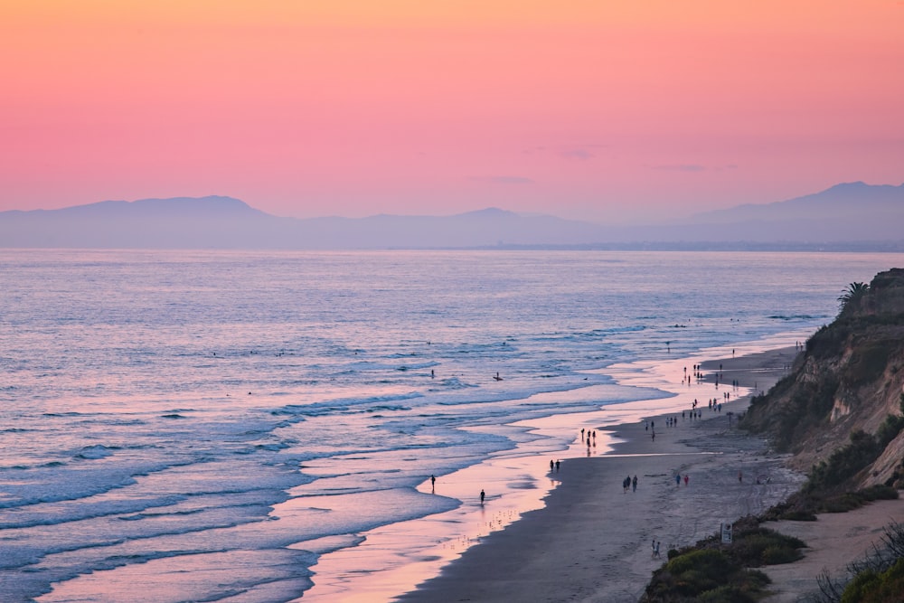 a body of water with a beach and mountains in the background