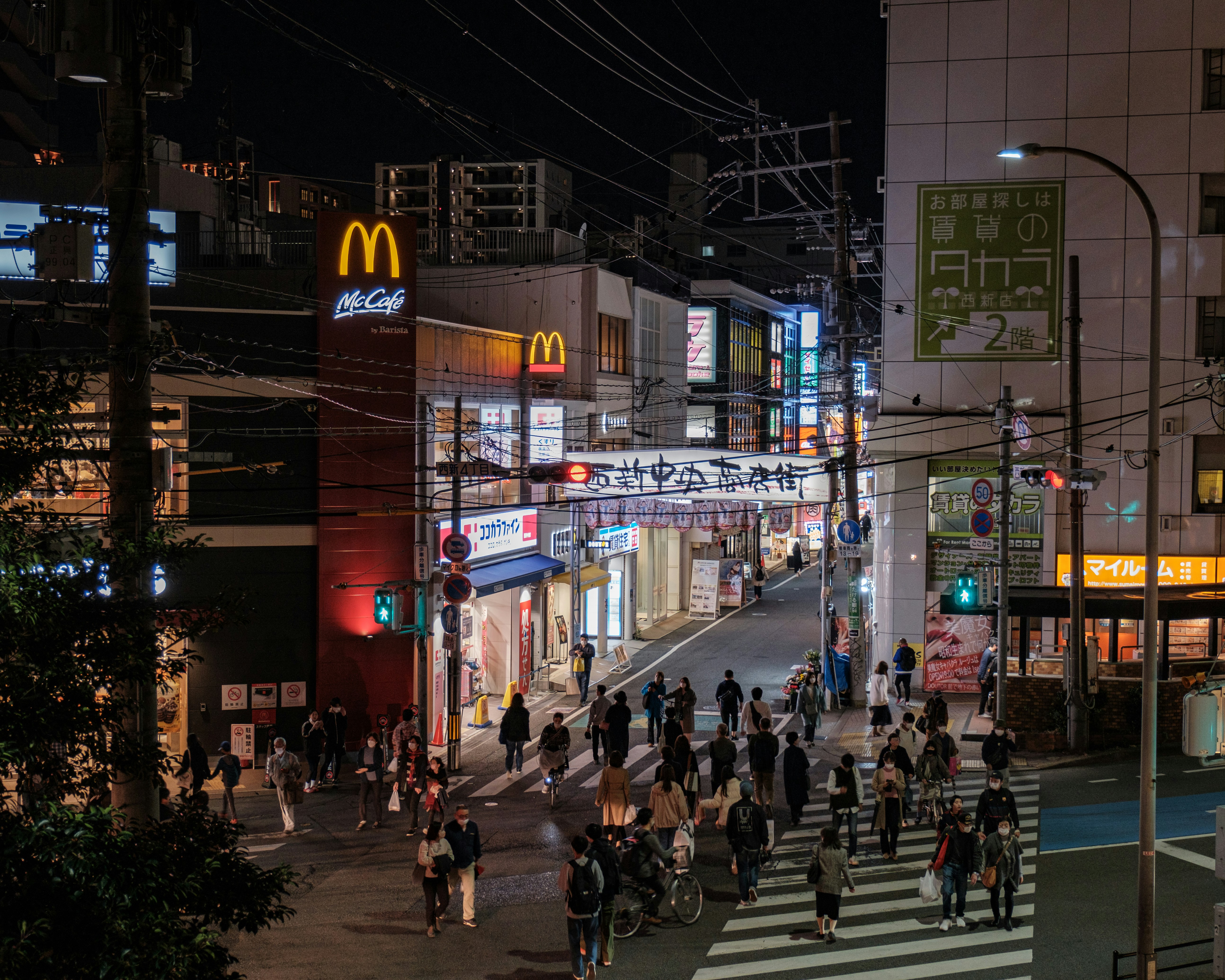 Street view of a Japanese shopping district at night, with various restaurant signs and plastic food displays