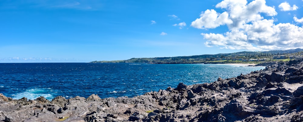 a rocky beach with a body of water in the background