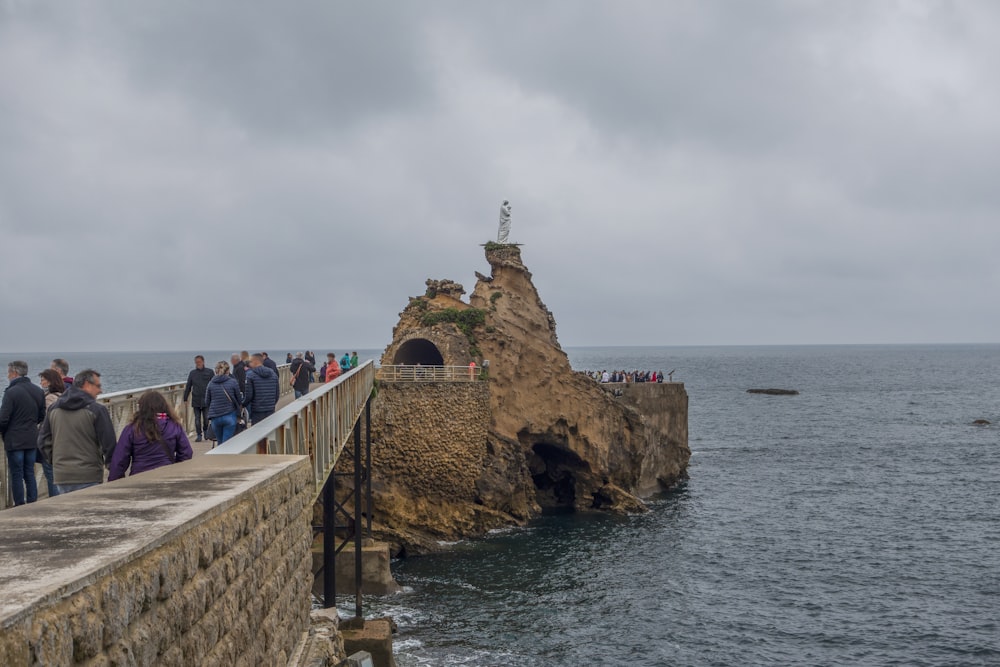 a group of people standing on a stone bridge over water