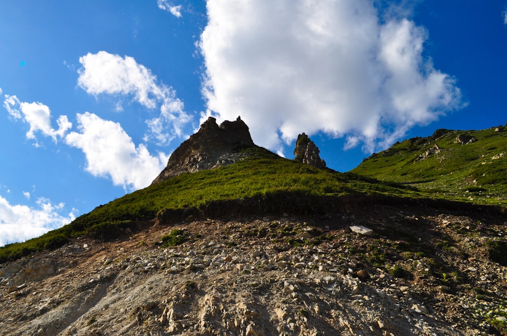 a grassy hill with a rock formation