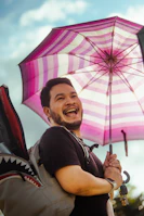 A joyful person dancing in the rain under a multicolored umbrella.