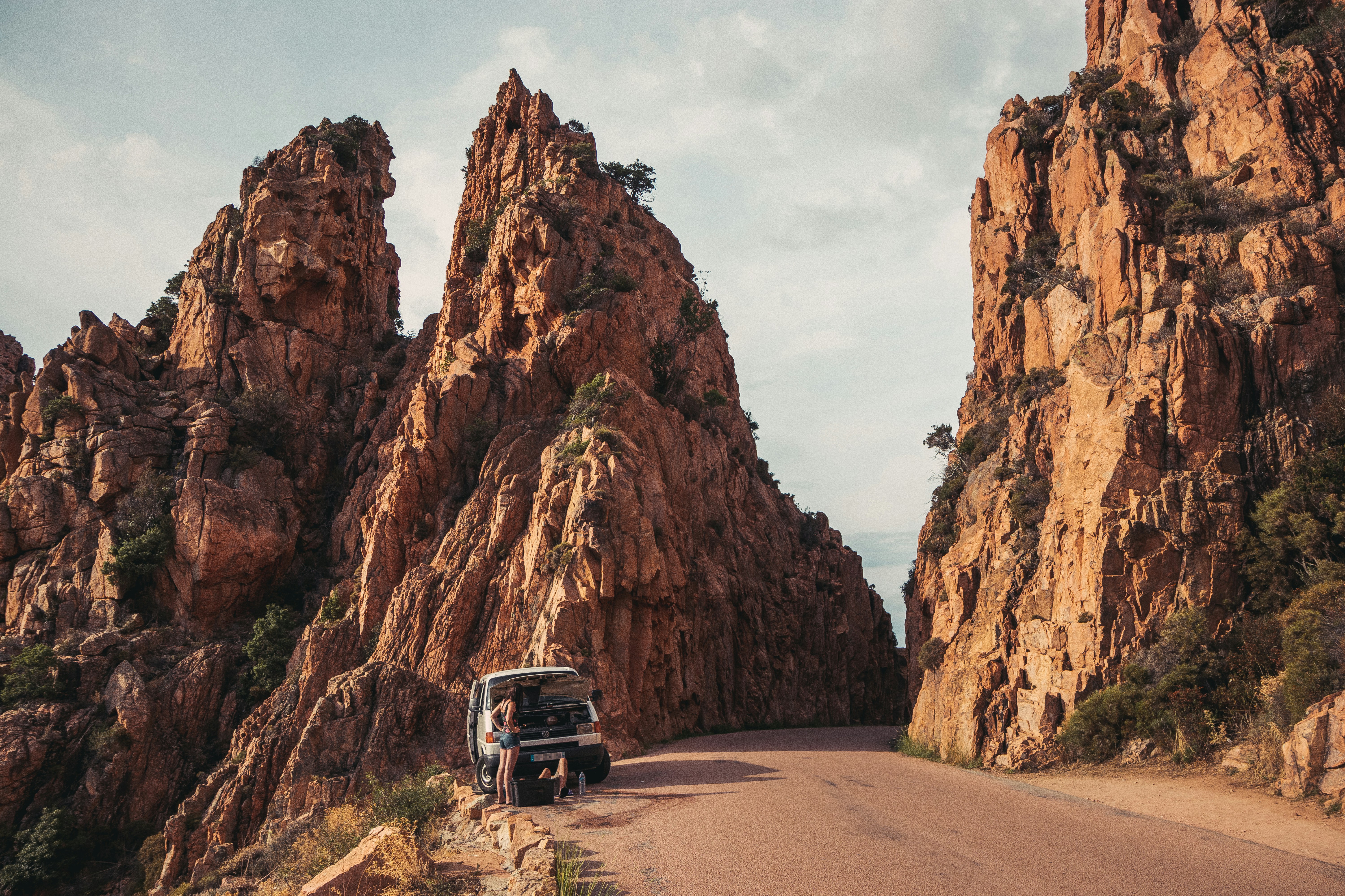 a truck driving down a road between large rocks