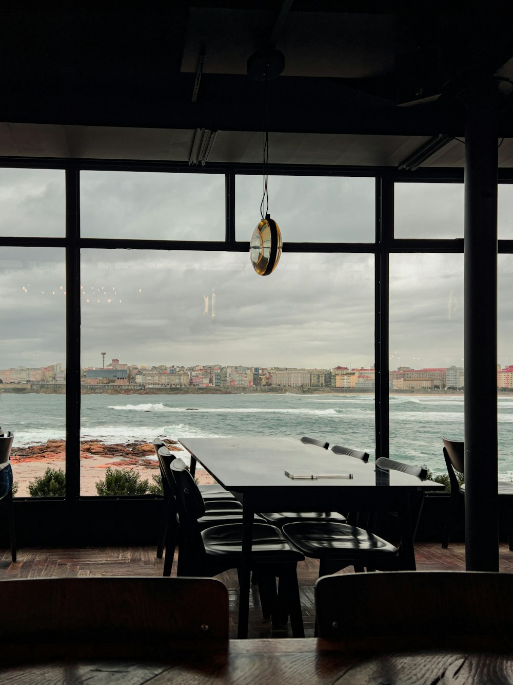 uma mesa e cadeiras em frente a uma janela com vista para um corpo de água