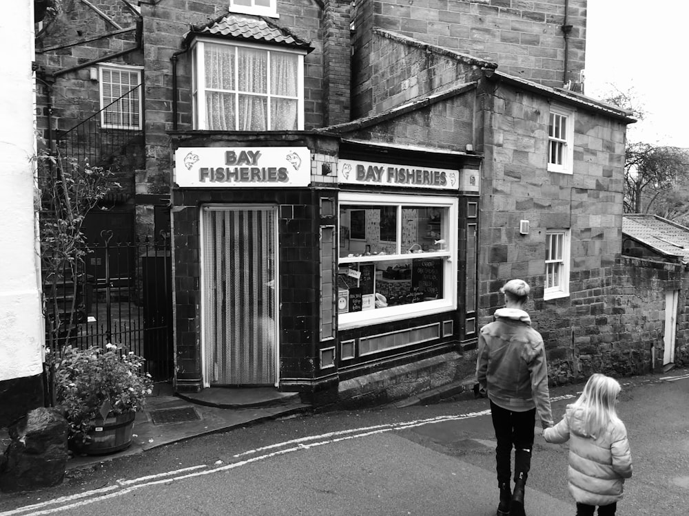 a couple of people walking by a small shop