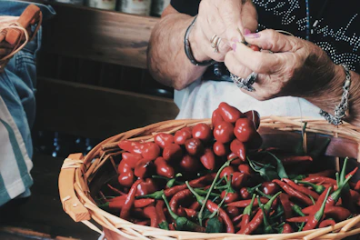 a person holding a basket of red peppers