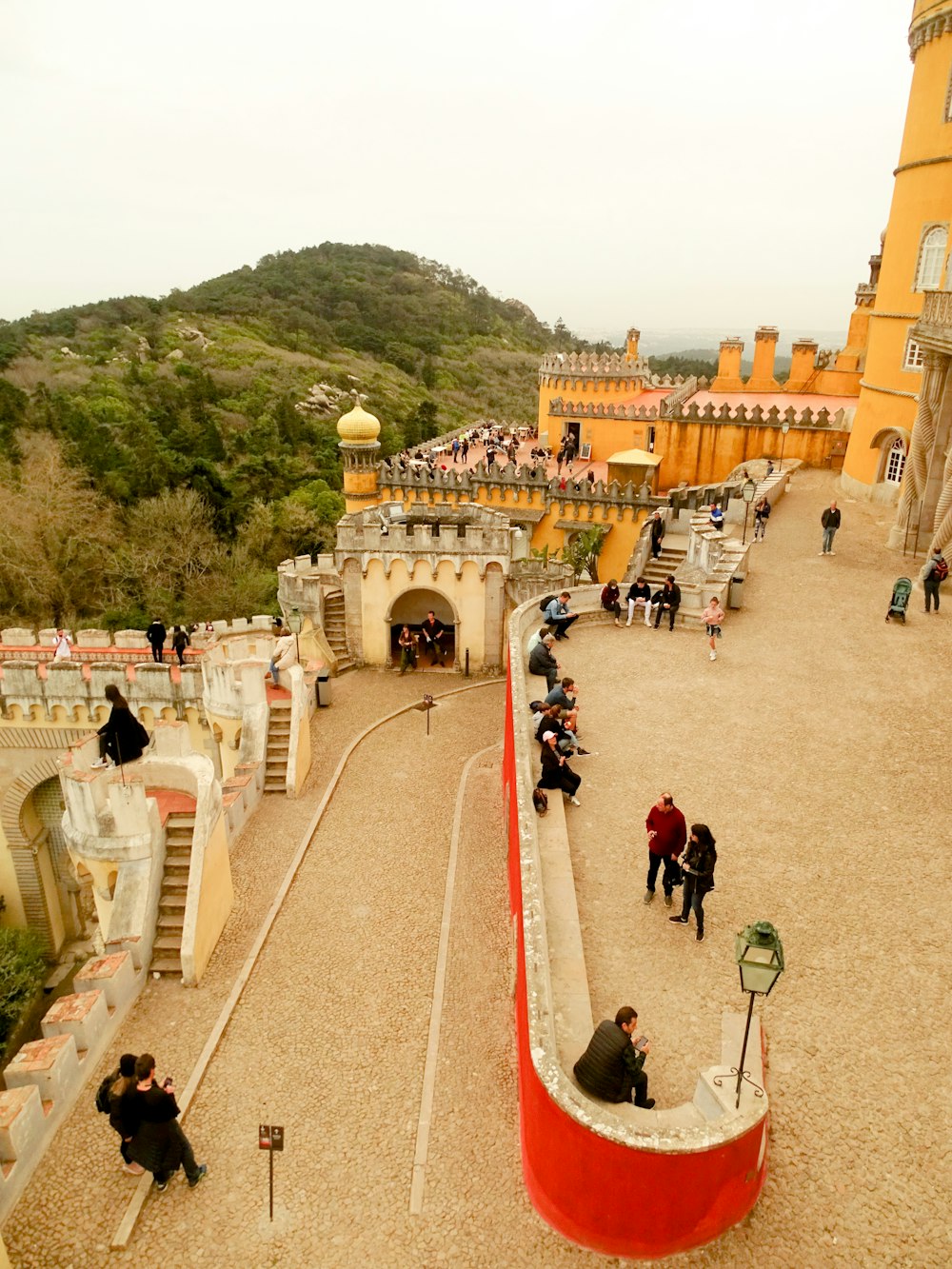 a group of people walking on a street next to a hill