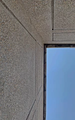 A panoramic view of a large warehouse wall constructed with precast concrete panels under a clear blue sky.