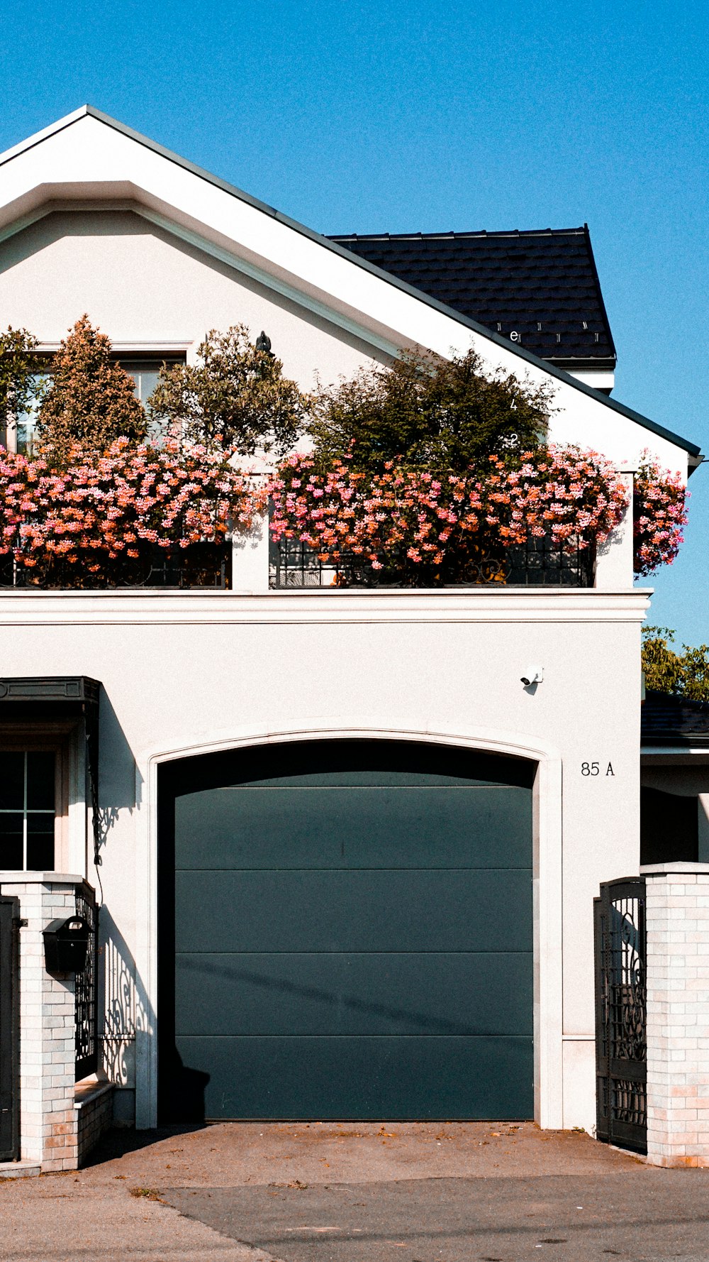 a building with a garage door and a tree with flowers on it
