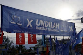 Photo of a community event with banners showing PC PMII Banyuwangi colors and logo.