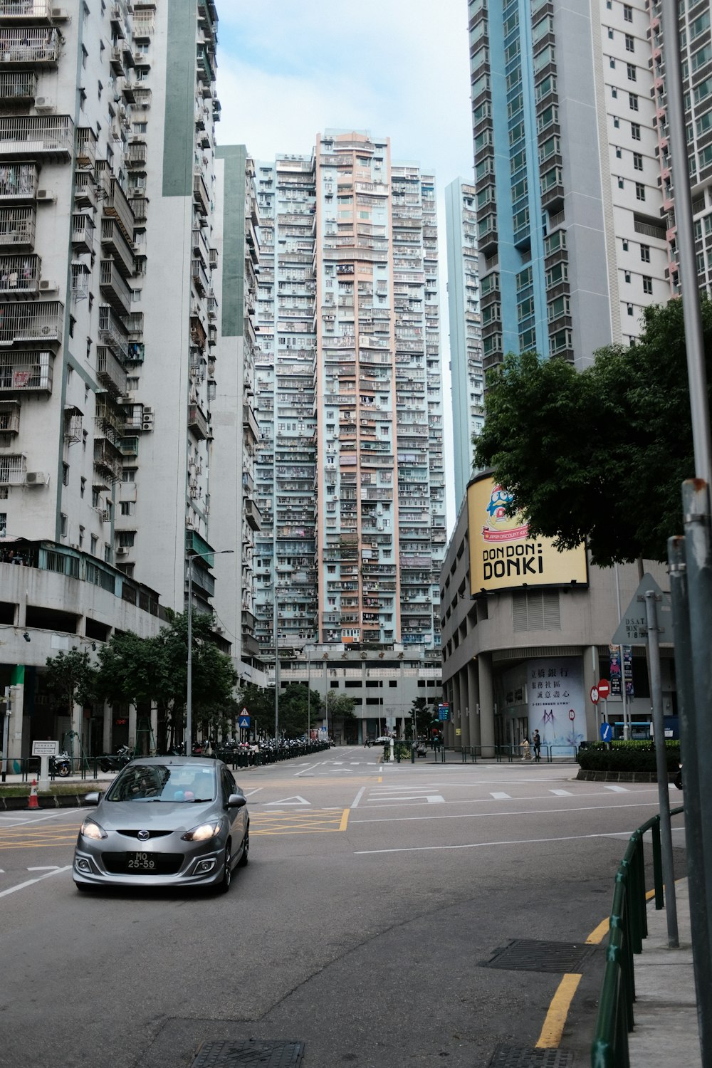 a car driving down a street between tall buildings