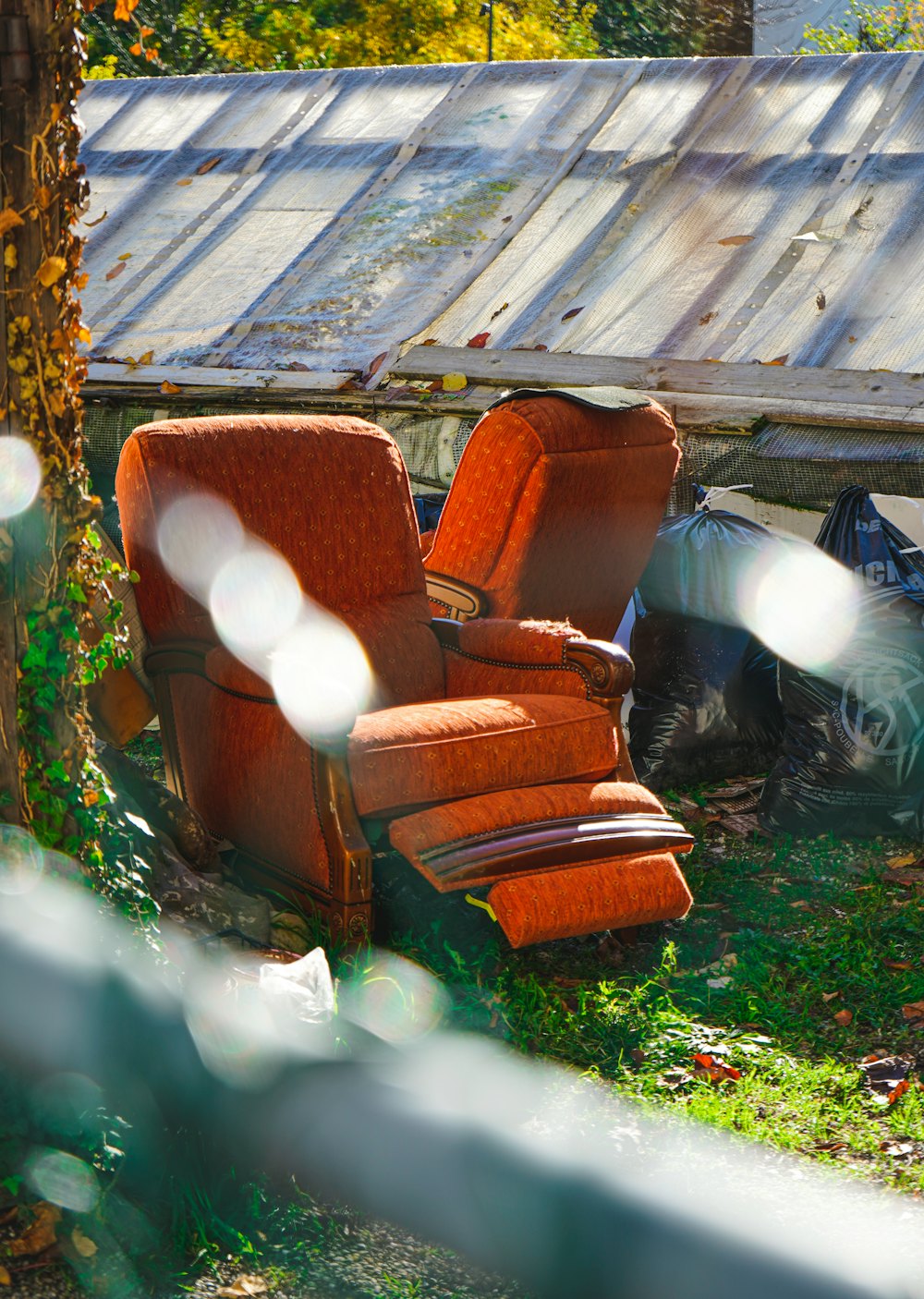 Worn armchairs and bagged junk set out for removal