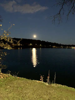 A serene lake reflecting the gentle glow of a full moon on a calm night.