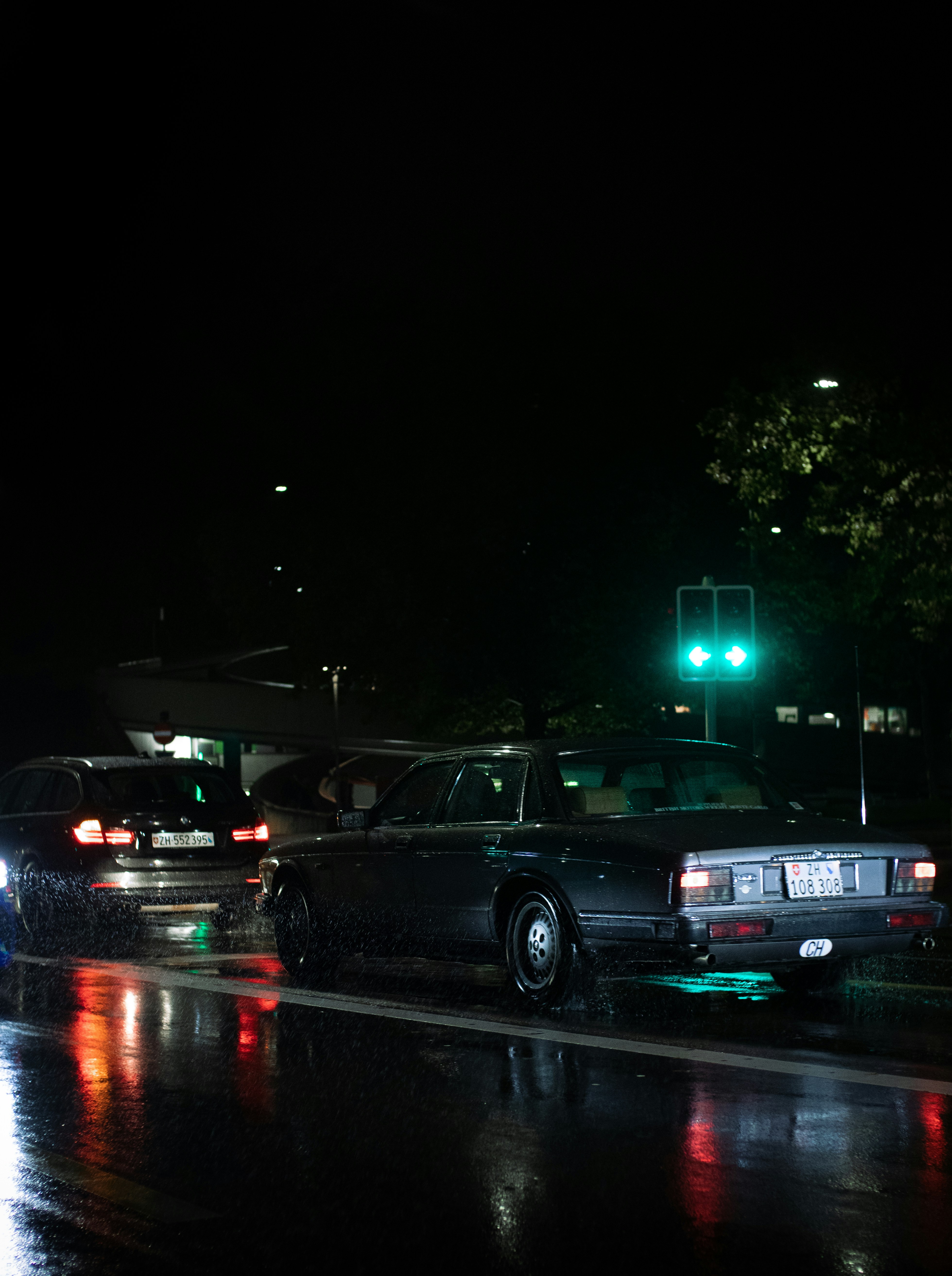 a couple of cars parked on a wet street at night