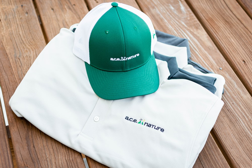 a green and white hat sitting on top of a white shirt