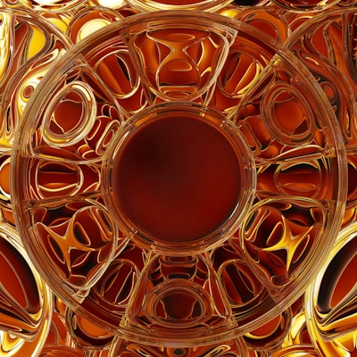A complex fractal pattern with circular and symmetrical designs, featuring a richly textured and reflective surface. The predominantly golden and amber hues create a sense of warmth and luxury.