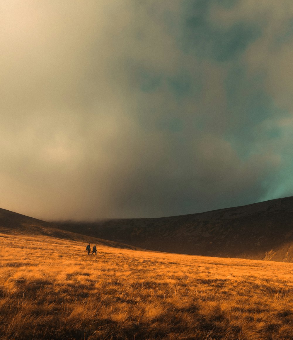 a group of people walking on a dirt road in a hilly area