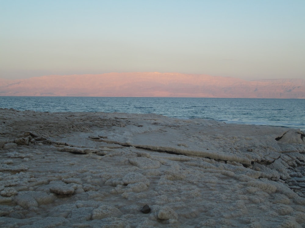 a rocky beach with water and a sunset