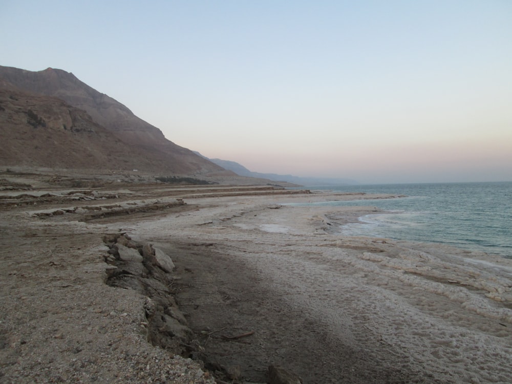 a sandy beach with hills and water