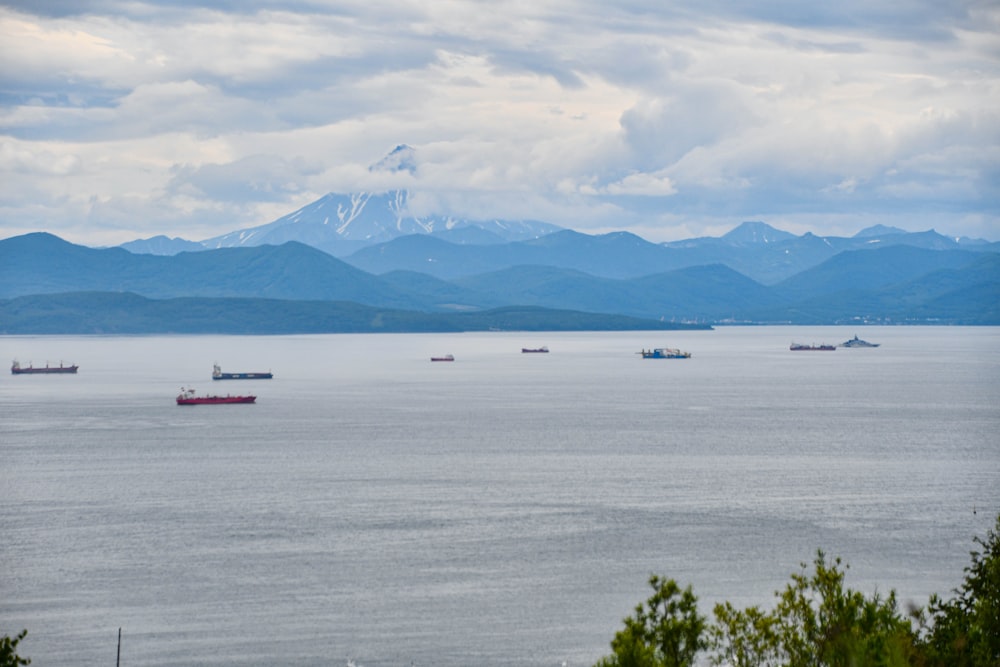 a group of boats in a body of water with mountains in the background