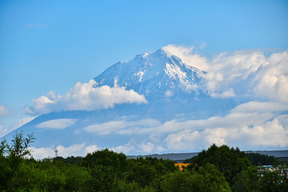 a mountain with clouds above trees