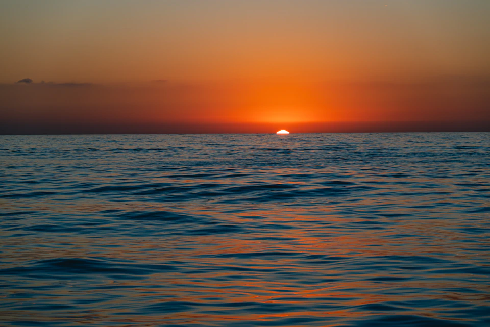 Sunset over the ocean with warm glow on the horizon and calm waters